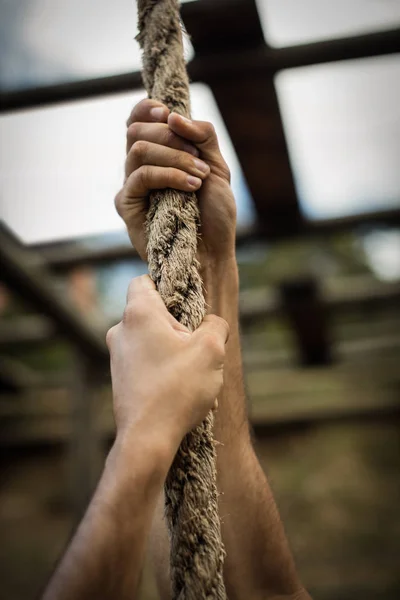 Man climbing a rope during obstacle course — Stock Photo, Image