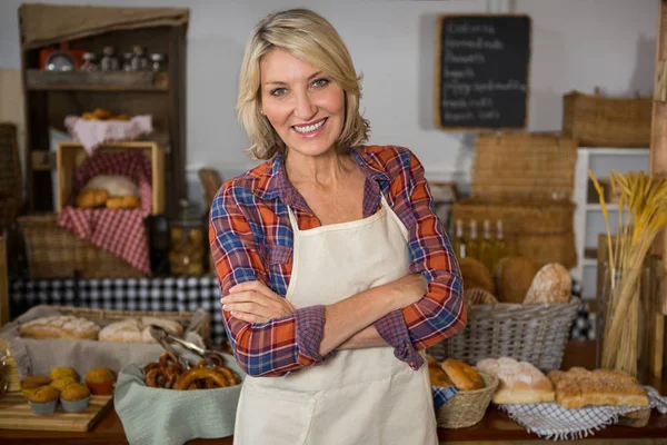 Retrato de sorridente feminino pessoal de pé com os braços cruzados no balcão — Fotografia de Stock