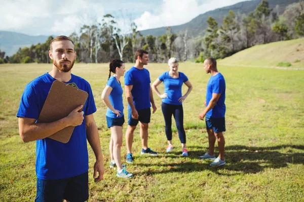 Fit homme debout et tenant un presse-papiers dans le camp d'entraînement — Photo