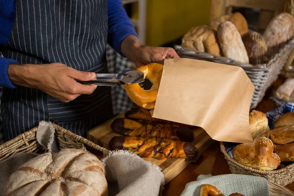 Középső szakasz csomagolás croissant papírzacskóban pultnál a személyzet — Stock Fotó