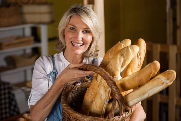 Personal femenino sosteniendo canasta de baguettes en sección de panadería — Foto de Stock