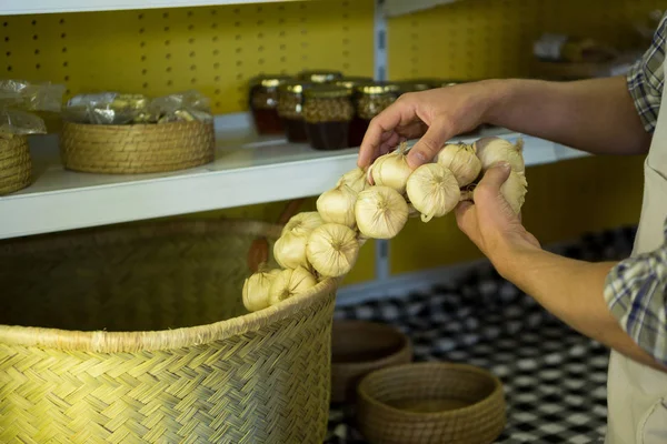 Mid-section of staff putting garlic in wicker basket — Stock Photo, Image