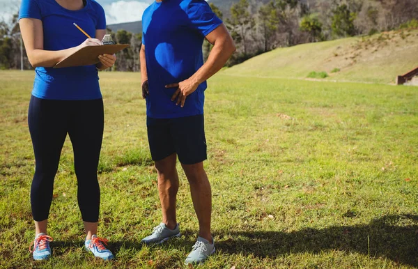 Entrenadora instruyendo a un hombre en el campo de entrenamiento —  Fotos de Stock