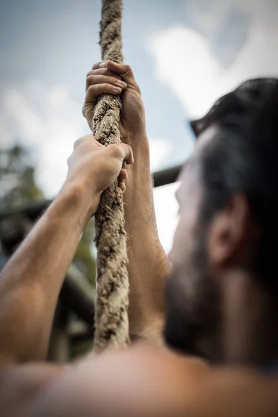 Man climbing a rope during obstacle course — Stock Photo, Image