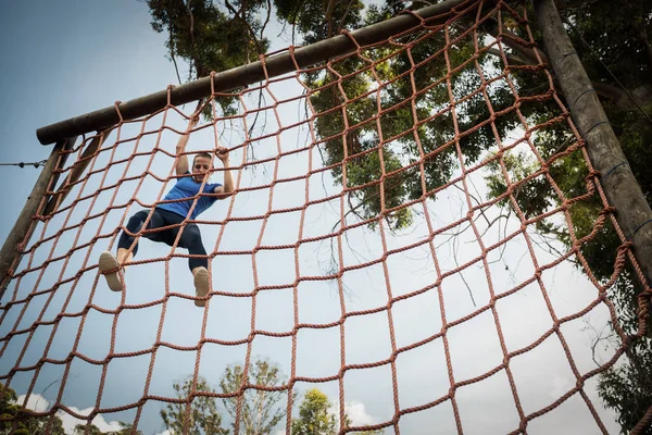 Woman climbing a net during obstacle course — Stock Photo, Image