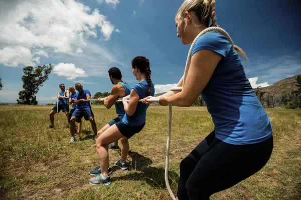Mensen spelen touwtrekken tijdens opleiding hindernissenparcours — Stockfoto