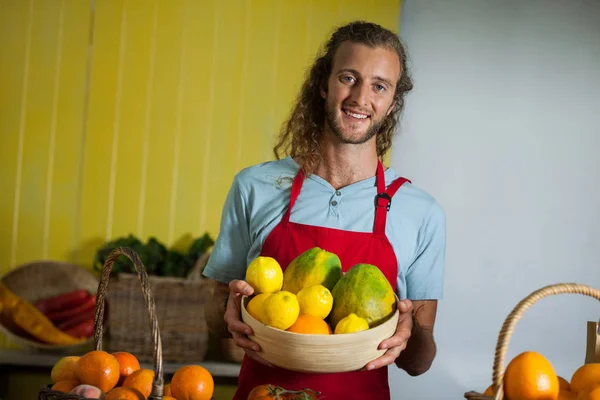 Smiling male staff holding fruits in basket at organic section — Stock Photo, Image