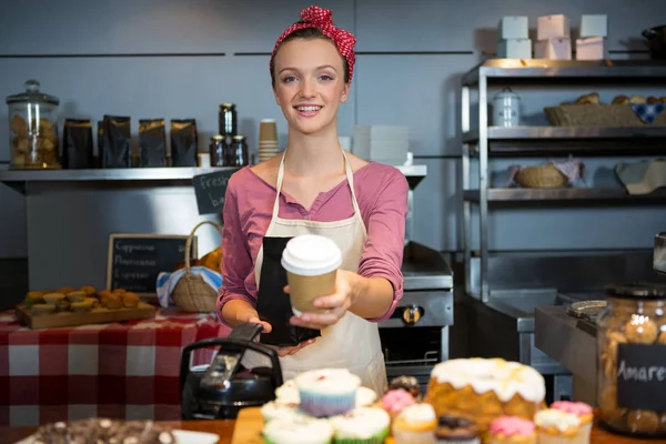 Portret van vrouwelijk personeel holding tas koffie en koffiekopje bij balie — Stockfoto