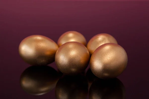 Золотые пасхальные яйца на цветном фоне — стоковое фото