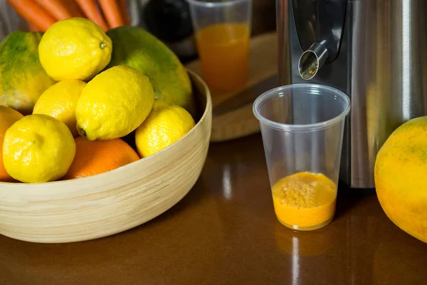 Limones en cuenco de madera con vaso de jugo en el mostrador — Foto de Stock