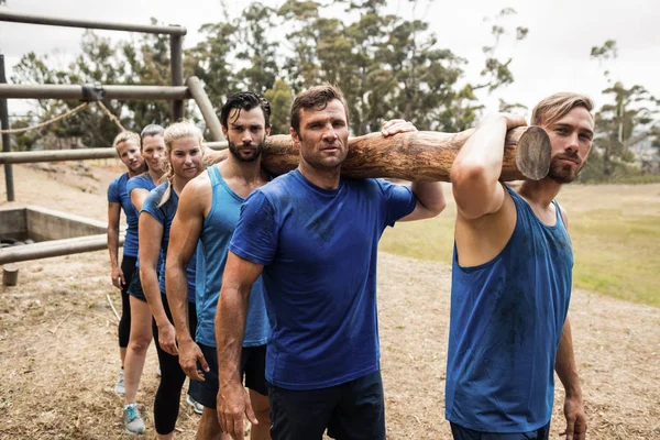 Mensen die een zware houten log tijdens boot camp — Stockfoto