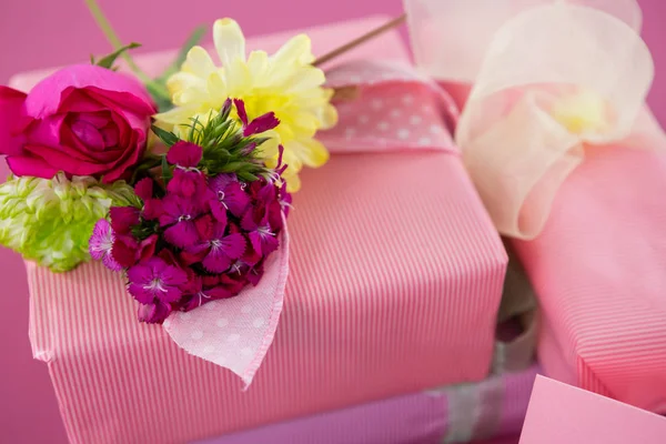 Presentaskar med blommor och tomt kort mot rosa bakgrund — Stockfoto