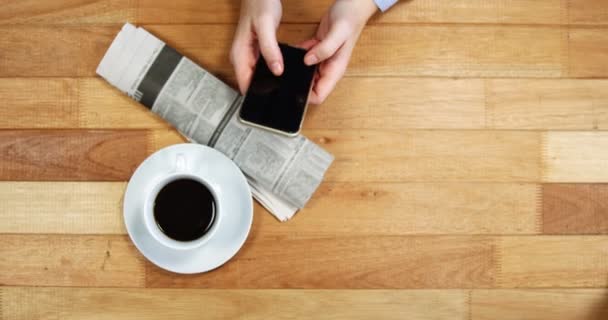 Empresaria usando teléfono móvil en el escritorio con periódico y taza de café en la mesa — Vídeos de Stock