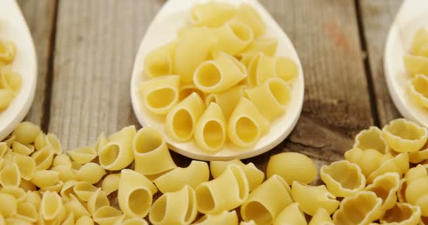 Verschillende pasta in lepels op houten achtergrond — Stockvideo