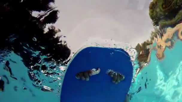 Мальчик плавает на доске для серфинга в бассейне — стоковое видео
