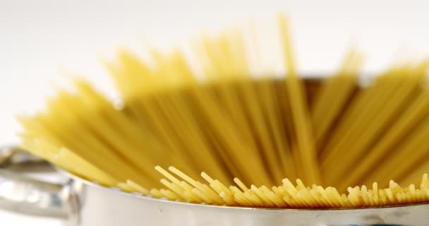 Сырые спагетти в контейнере на белом фоне — стоковое видео