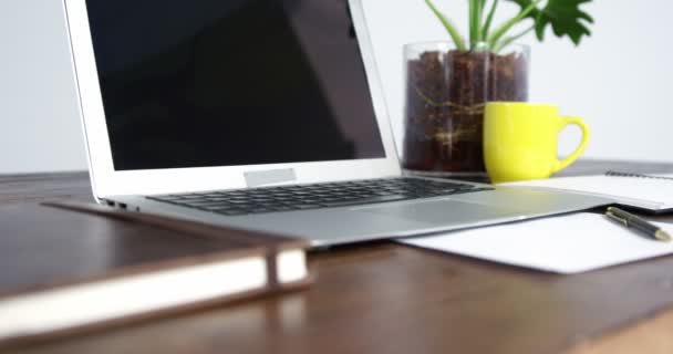 Laptop, notitieboekje en kopje koffie gerangschikt op houten tafel — Stockvideo