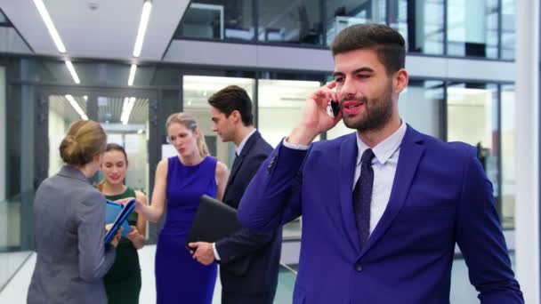 Uomo d'affari che parla sul cellulare mentre gli uomini d'affari discutono in background — Video Stock