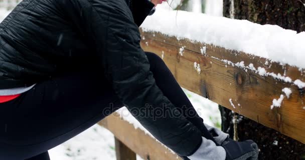 美丽的女人在降雪期间绑鞋带 — 图库视频影像