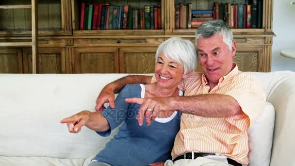 Seniorenpaar sitzt zusammen auf Sofa und schaut fern — Stockvideo