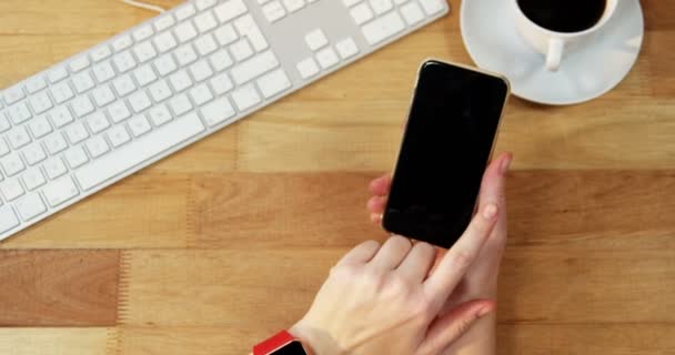 Mano de mujer de negocios usando el teléfono móvil en el escritorio — Vídeos de Stock