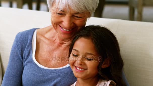 Бабуся і онука взаємодіють, дивлячись на фотоальбом у вітальні — стокове відео