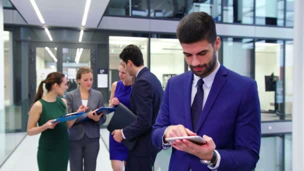 Biznesmen za pomocą cyfrowego tabletu podczas dyskusji w tle biznesmeni — Wideo stockowe