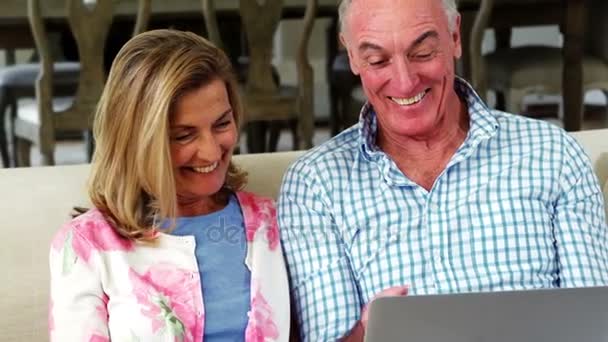 Glimlachend senior paar met laptop in de woonkamer — Stockvideo