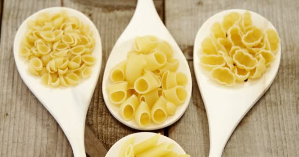 Verschillende pasta in lepels op houten achtergrond — Stockvideo
