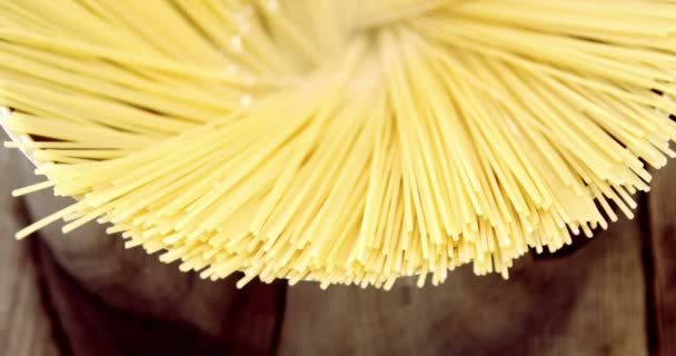 Сырые спагетти в контейнере на деревянном столе — стоковое видео