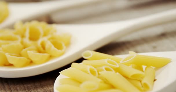 Verschillende pasta in lepels op houten achtergrond — Stockvideo