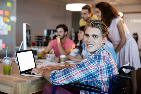 Smiling man using laptop while working with his team in office — Stock Photo, Image