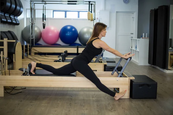 Donna determinata che pratica esercizio di stretching sul riformatore — Foto Stock
