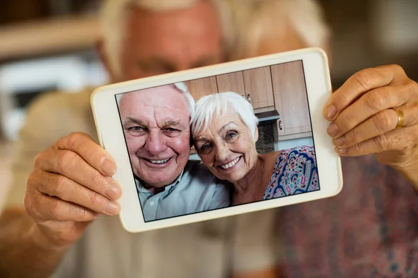 Старшая пара делает селфи из цифрового планшета на кухне — стоковое фото