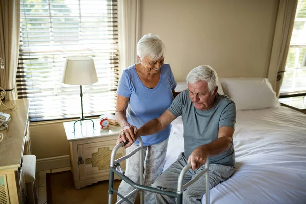 Senior woman helping man to walk with a walker — Stock Photo, Image