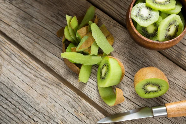 Rebanadas y kiwi pelado sobre mesa de madera —  Fotos de Stock