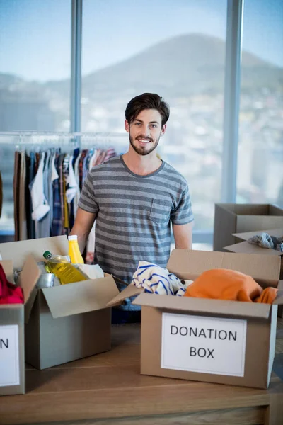 Улыбающийся человек, стоящий с коробкой для пожертвований в офисе — стоковое фото