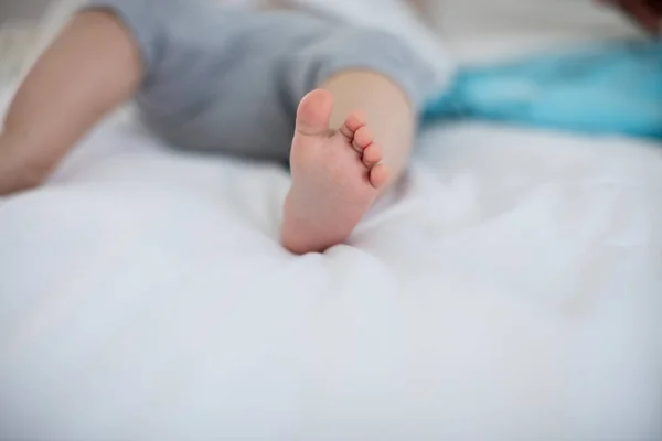 Primer plano de pies de niña relajándose en la cama — Foto de Stock