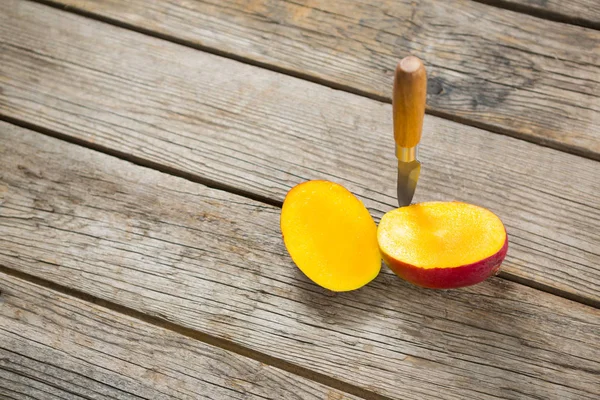 Mango a la mitad y cuchillo en mesa de madera —  Fotos de Stock