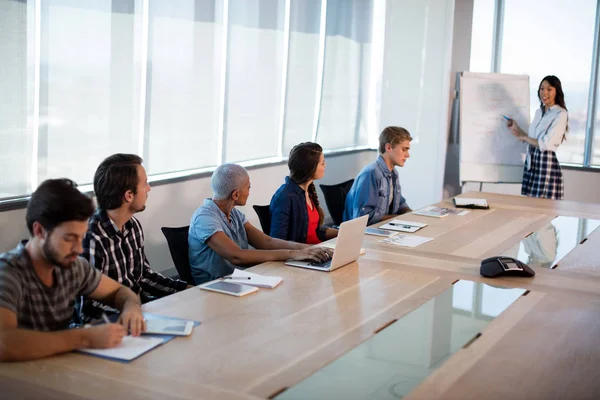 Kvinnan ger presentation till kollegorna i konferensrum — Stockfoto