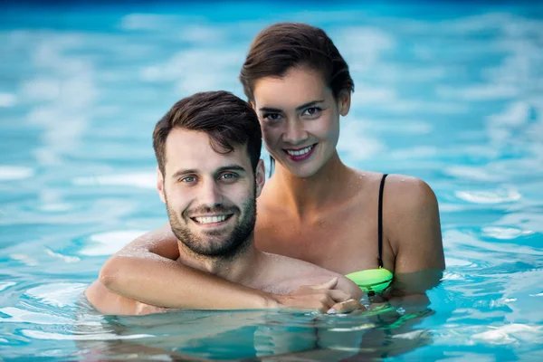 Ungt par omfamnar varandra i poolen — Stockfoto