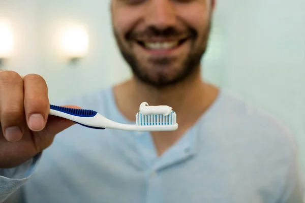 Primer plano del joven feliz sosteniendo el cepillo de dientes con pasta de dientes — Foto de Stock