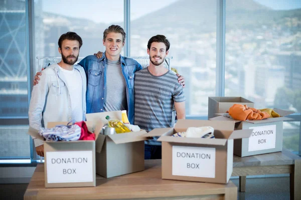 Smiling creative business team standing with donation box in office — Stock Photo, Image