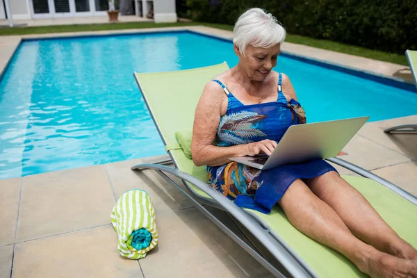 Senior vrouw met laptop op lounge stoel — Stockfoto