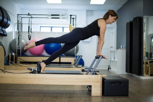 Mujer decidida practicando ejercicio de estiramiento en reformador —  Fotos de Stock