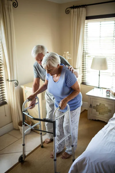 Senior mannen att hjälpa kvinnan att gå med en walker — Stockfoto