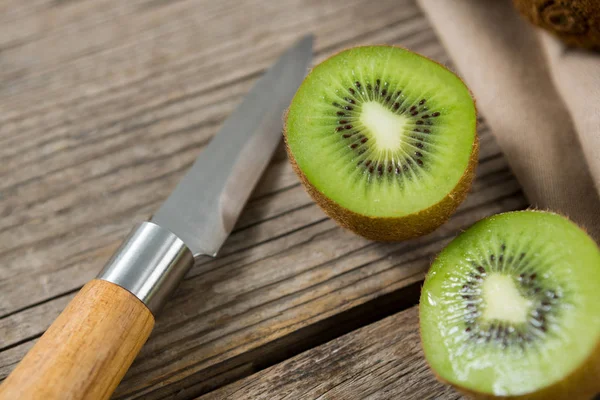Kiwis с ножом на деревянном столе — стоковое фото