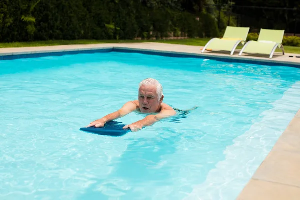 年配の男性がプールで泳いで — ストック写真