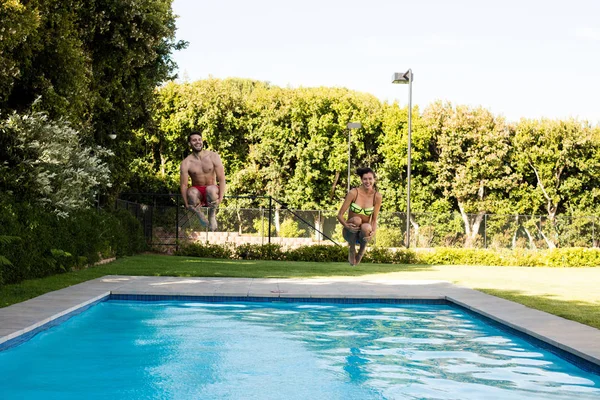 Giovane coppia che salta insieme in piscina — Foto Stock