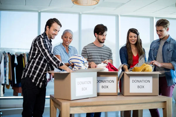 Креативная бизнес-команда спаивает одежду в коробке для пожертвований — стоковое фото